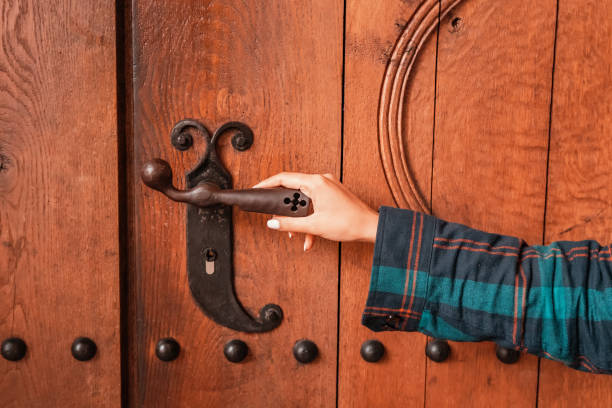 tourist girl enters the wooden door of a small chapel or church in the old town square. Take to religion concept